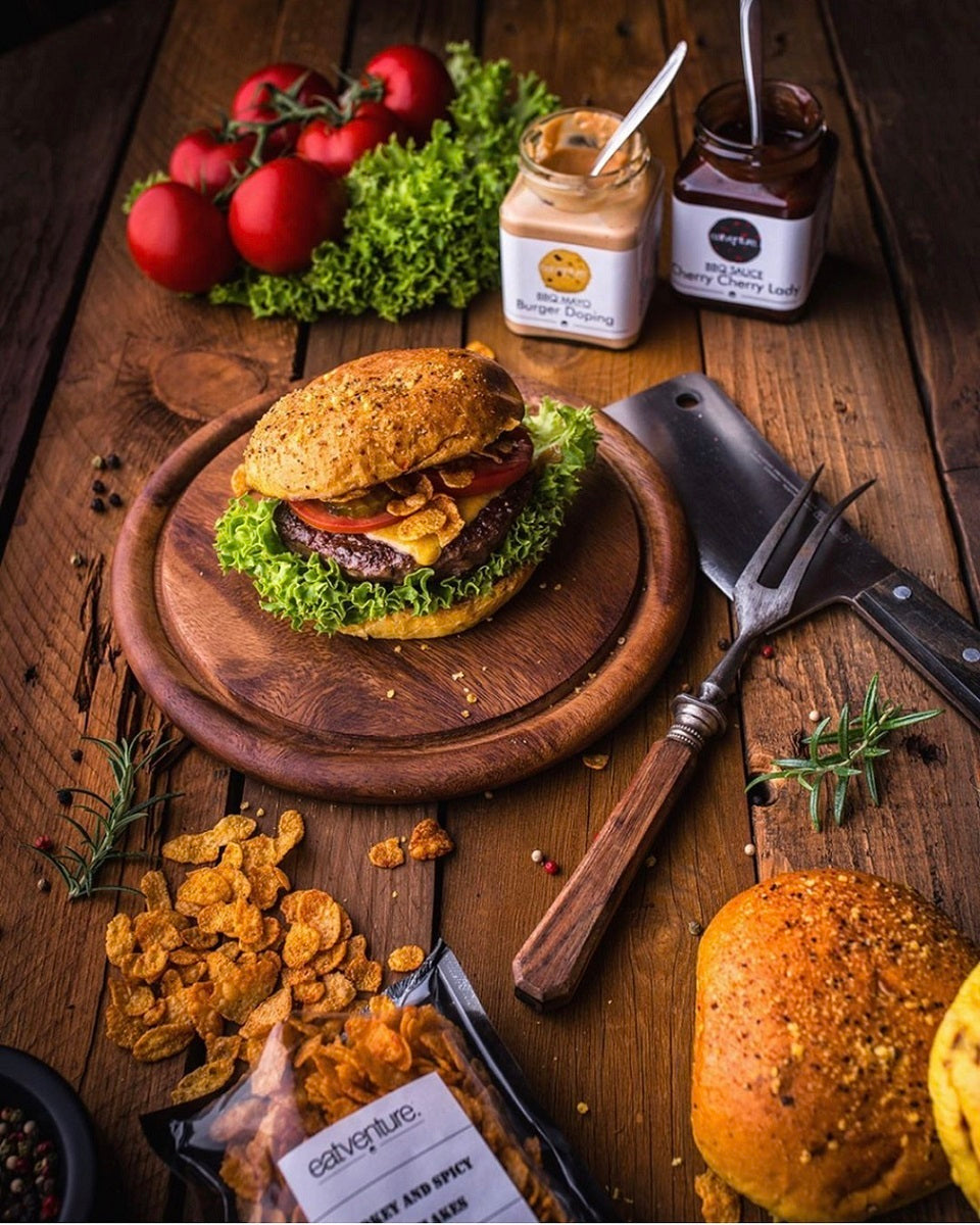 Ein Eatventure Burger mit Black Angus Burger Pattie auf einem Holzbrett serviert